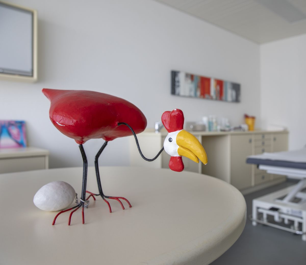 Kleine Skulptur eines Huhns mit einem Ei, das am Bein angekettet ist